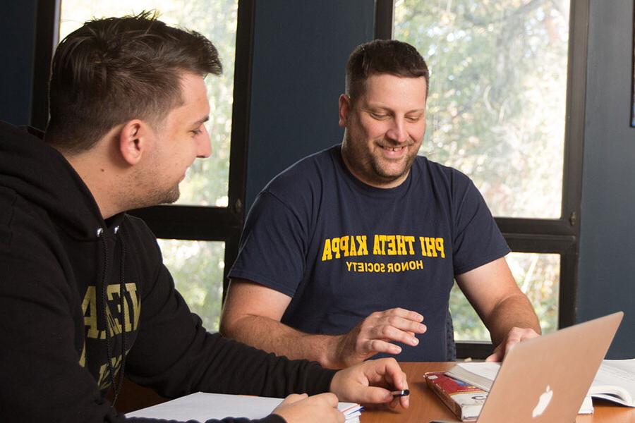 Two male students at a conference table. One students sweatshirt reads Phi Theta Kappa Honors Society.
